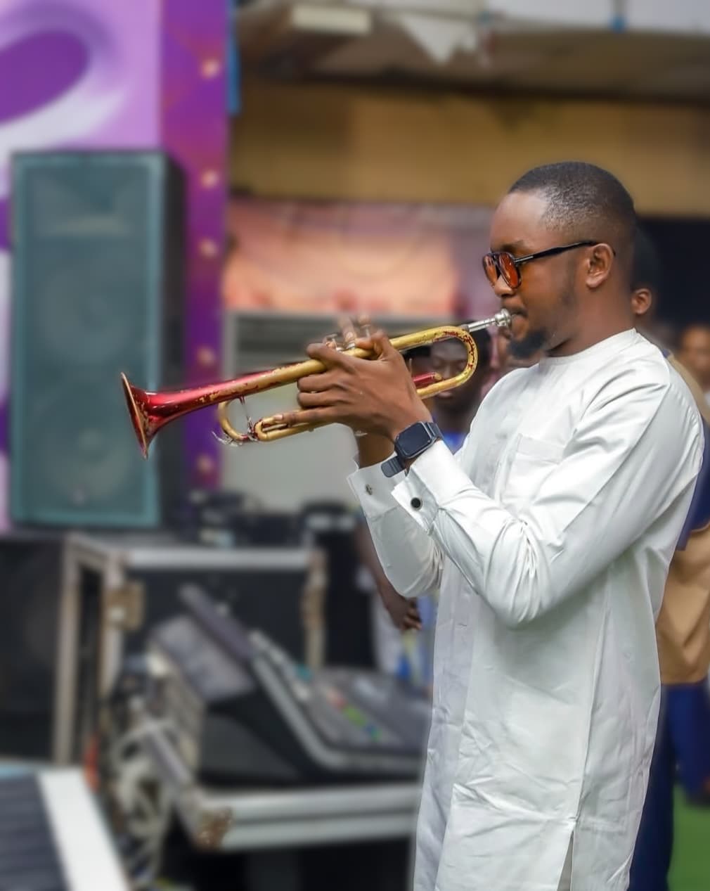 Oladimeji playing trumpet beside a mixing desk